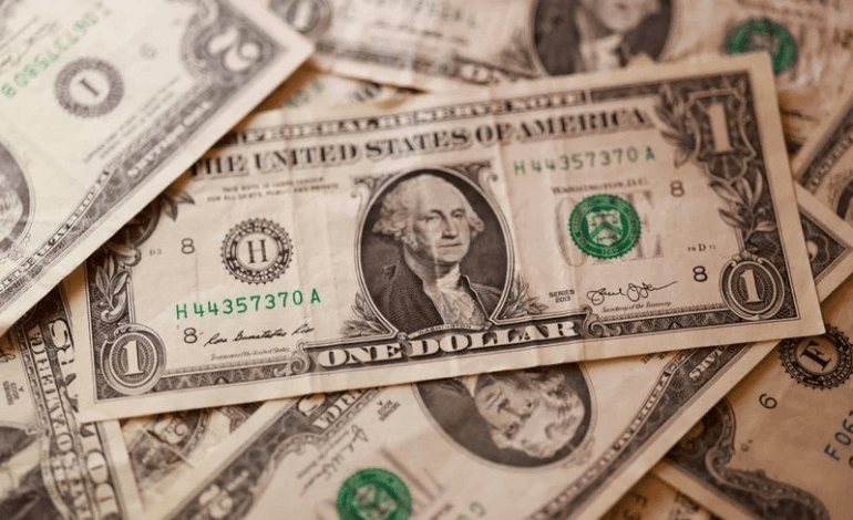 Billetes de dolares estadounidenses junto a una calculadora y graficos financieros